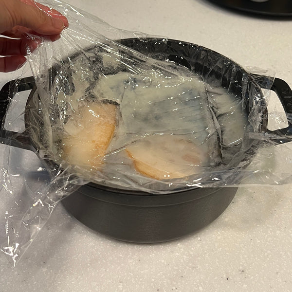 removing the plastic wrap from the pork broth once it has cooled